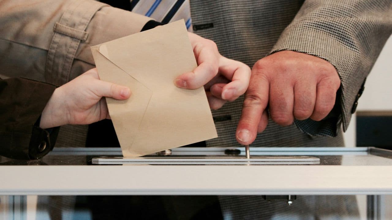Manos depositando un sobre en una urna